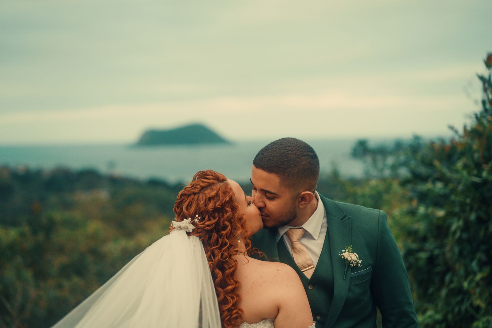 Noivos se beijando com vista para o mar