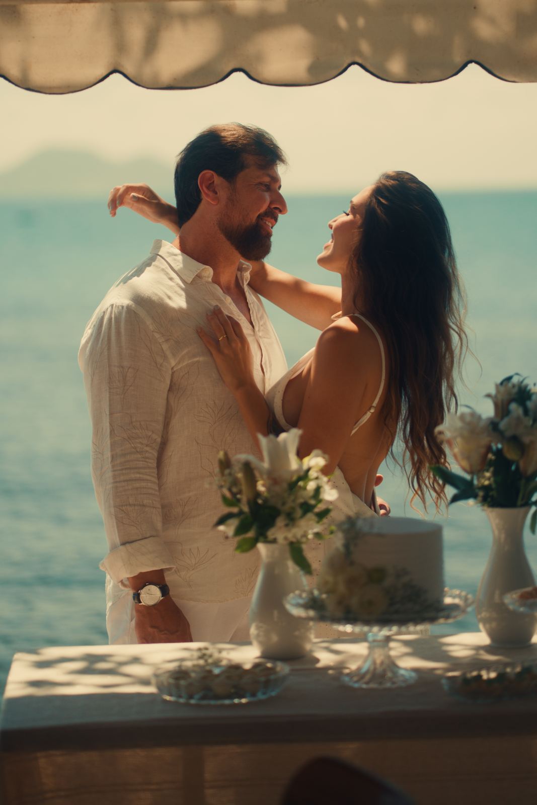 Casal celebrando com bolo e vista para o mar