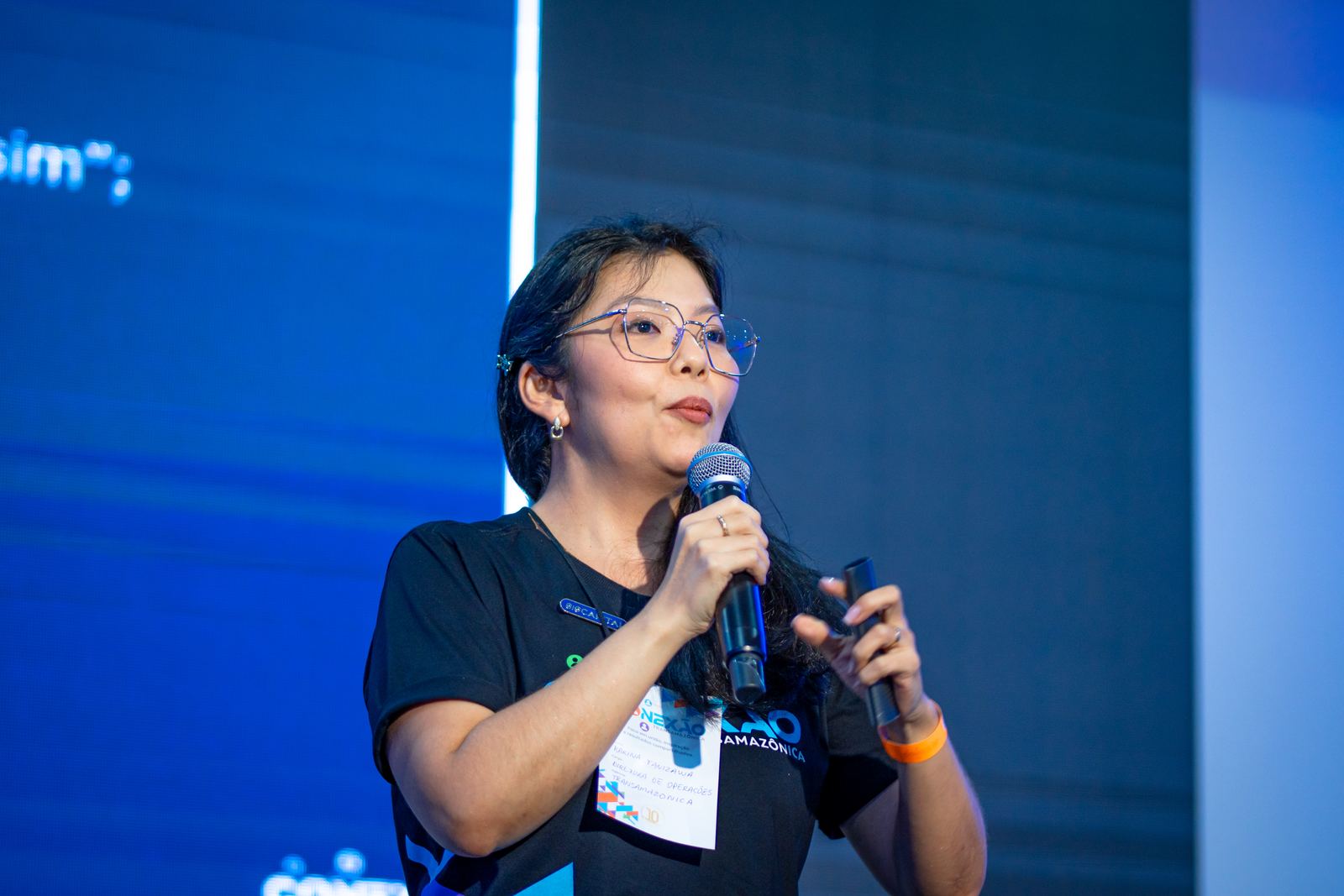 Palestrante falando ao microfone em evento corporativo