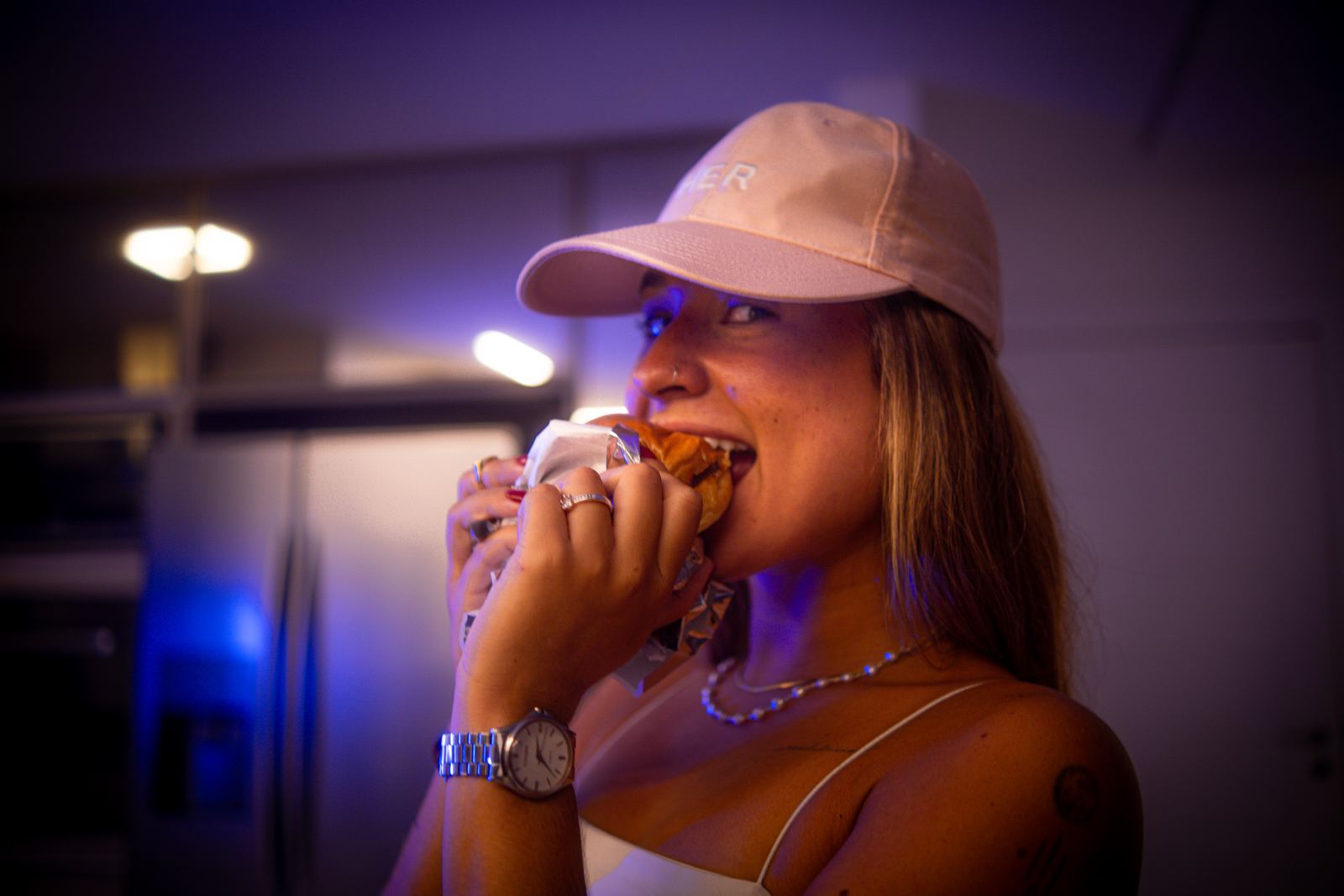 Cliente mordendo hambúrguer em luz neon