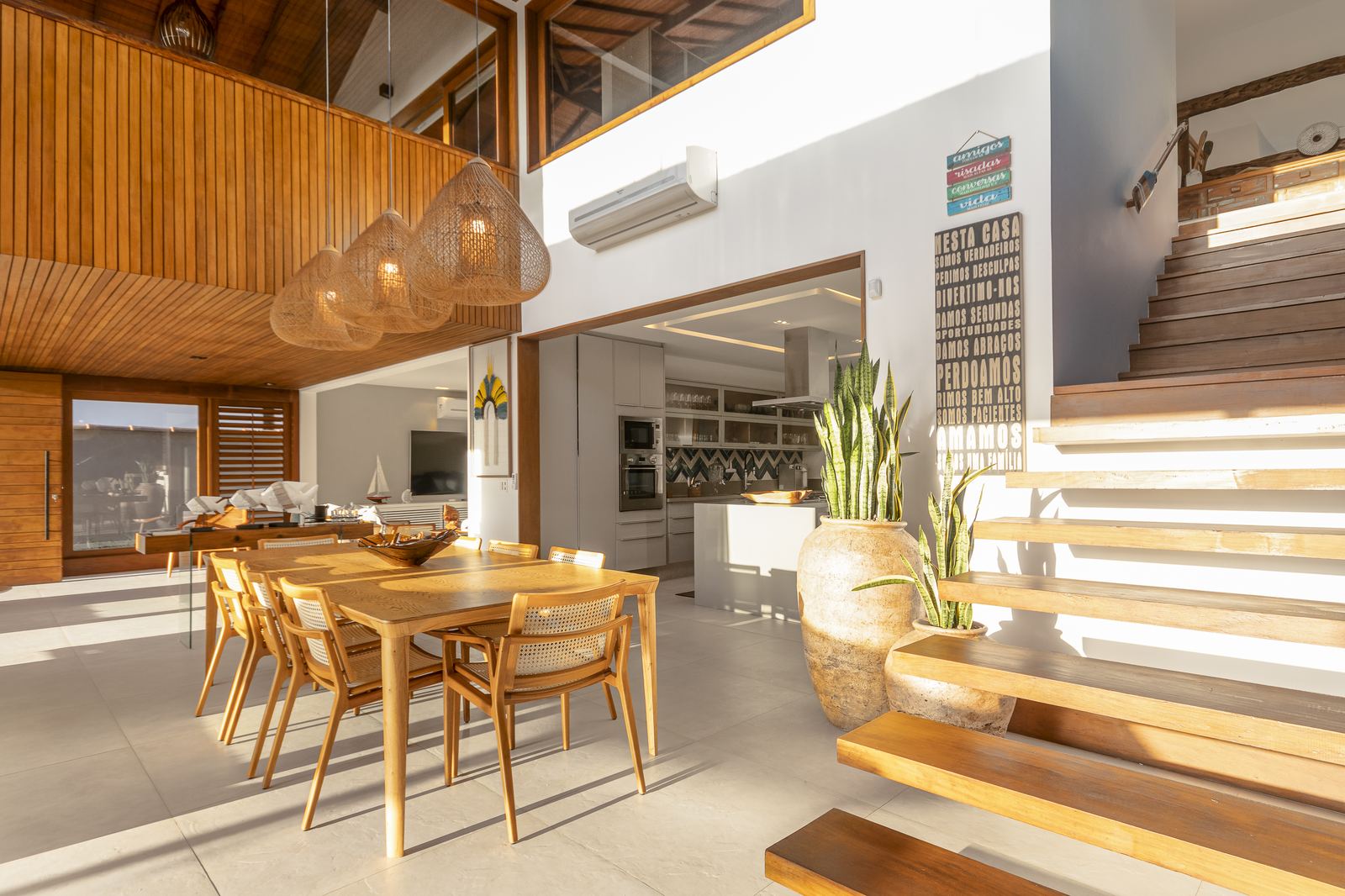 Sala integrada com mesa de jantar e escada de madeira
