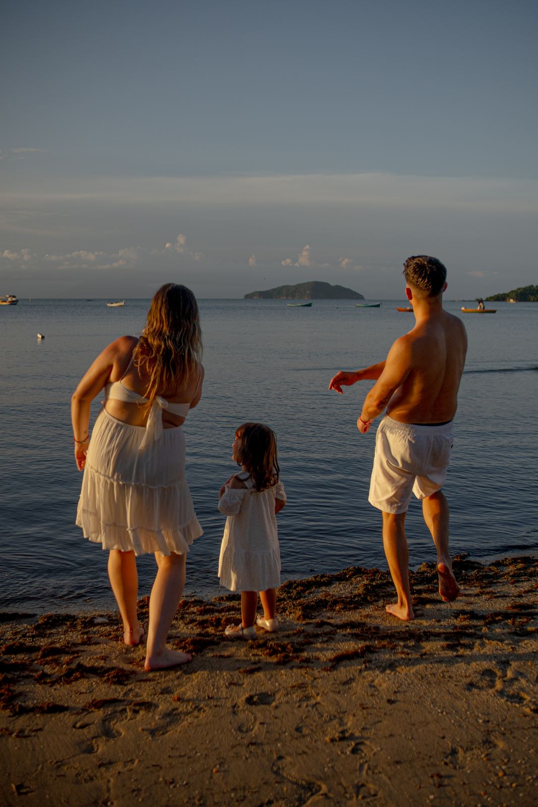 Família na beira da praia ao entardecer